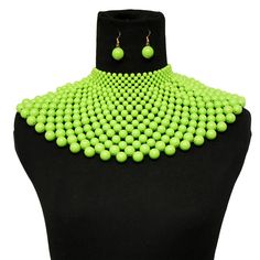 a green necklace and matching earrings on a mannequin with a black headpiece