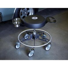 a stool with wheels on the floor next to a car