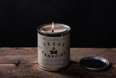 a candle that is sitting on top of a table next to a canister with the lid open