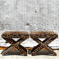 two leopard print benches sitting in front of a white wall