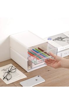 a person's hand is holding a pen and pencils in a clear box