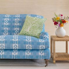 a blue and white couch sitting next to a vase with flowers