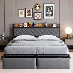 a bed with two drawers underneath it in a room that has gray walls and pictures on the wall