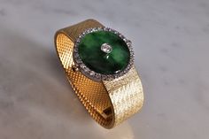 "Fine watch bracelet set with a jade donut and accented with diamonds in 18k. The donut is a deep green Omphacite jade, in parts dark and light like a globe lit. This jewel borrows the perfect finish of a Vacheron watch, its Omega straps in original burnished solid gold. More than a conversion piece, this bracelet could not have been refined to a sleeker layout. At 2cm, the donut is considered big yet its size is offset by the straps, and vice versa. The straps though wide feel made for its cent Green Polished Jewelry For Evening, Polished Green Jewelry For Evening, Green Polished Evening Jewelry, Green Polished Finish Evening Jewelry, Evening Bracelets With Polished Finish, Formal Round Jade Jewelry, Luxury Green Diamond Watch For Formal Occasions, Green Luxury Diamond Watch For Formal Occasions, Luxury Jade Jewelry