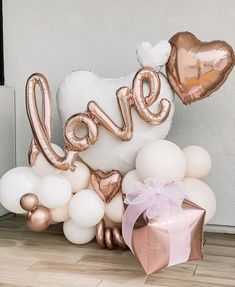 the balloon love sign is surrounded by white and rose gold balloons