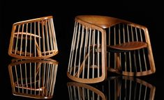 two wooden chairs sitting next to each other on top of a black surface in the dark