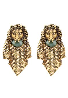 The lion head holds a green cabochon glass stone and is enriched with an intricate diamond-shaped beaded mesh detail. Metal with aged gold finish Lion head with agate green coloured cabochon glass stone Mesh metal detailAntique effect gold-tone hardware, Clip-on Lion head: 35mm x 40mm 86mm total length Material: Brass, cabochon glass stone, leaded crystalMade in Italy Chevron Jewelry, Gucci Runway, Lion Earrings, Head Chain, Buy Gucci, Chain Mail, Lion Head, Online Earrings, The Lion