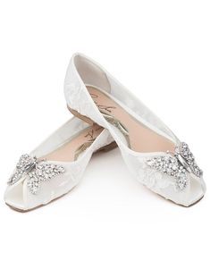 two pairs of white shoes with bows on them