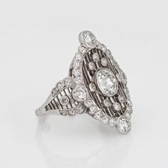 Stylish antique Edwardian diamond crafted in 900 platinum (circa 1910s).   Center set old European cut diamond is estimated at 0.75 carats (estimated at I-J color and VS2 clarity). Old European cut diamonds surround the center diamond and total an estimated 0.67 carats (estimated at I-J color and SI1-I1 clarity). The total diamond weight is estimated at 1.42 carats.   This one is for the books! A spectacular Edwardian era dinner ring highlights a bright and lively center set old European cut diamond, with a surround of shimmery diamonds set into an open work lattice mount. The cocktail ring is larger in scale (north to south measuring 24mm - 0.94 inches) and makes a great statement on the hand. The low rise ring (4.5mm - 0.17 inches) sits flat and comfortably on the finger. The original Ed Art Deco Oval Platinum Diamond Ring, Art Deco Oval Cluster Ring In Platinum, Oval Diamond White Cluster Ring With Single Cut Diamonds, Oval Cluster Ring With Single Cut Diamonds In White, Art Deco Oval Cluster Ring With Center Stone, Oval Diamond Ring With Platinum And Diamond Accents, Oval Platinum Diamond Ring With Diamond Accents, Oval Platinum Diamond Ring With Accents, Victorian Oval Diamond Ring With Halo Setting