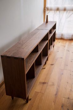 a wooden shelf sitting on top of a hard wood floor in front of a window