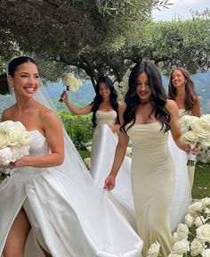 the bridesmaids are all dressed in white dresses and holding bouquets while walking down the aisle