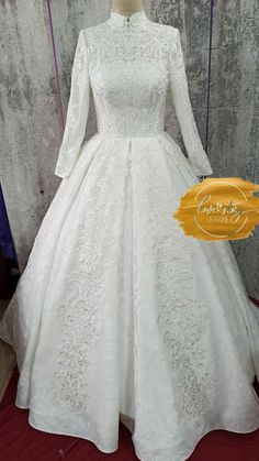 a white wedding dress with long sleeves and a high neckline on display in front of a