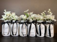 six mason jars with white flowers in them