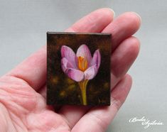 a small painting of a pink flower in someone's hand