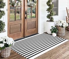 the front porch is decorated with wreaths and potted plants