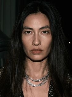 a woman with long black hair wearing a silver choker and necklace on her neck