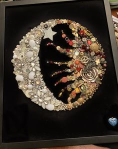 a black frame holding a large assortment of beads and other items in the shape of a crescent