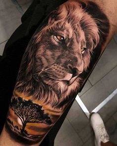 a man's arm with a lion and tree tattoo on the left side of his arm