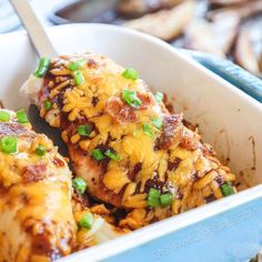 chicken covered in cheese and green onions in a casserole dish