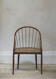 a wooden chair sitting on top of a hard wood floor next to a white wall