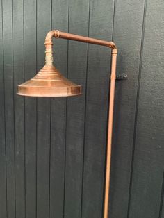 a copper colored lamp on a wooden floor next to a green wall with wood planks