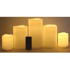 five lit candles and a remote control sitting next to each other