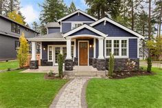 a blue house with white trim and brick walkway leading to the front door is surrounded by green grass