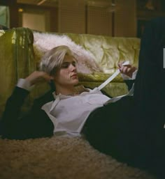 a woman laying on the floor with scissors in her hand next to a man who is wearing a suit and tie