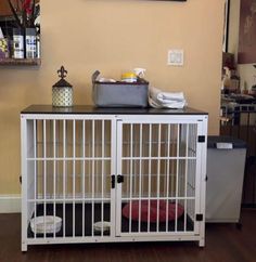 a white dog crate sitting on top of a hard wood floor next to a wall