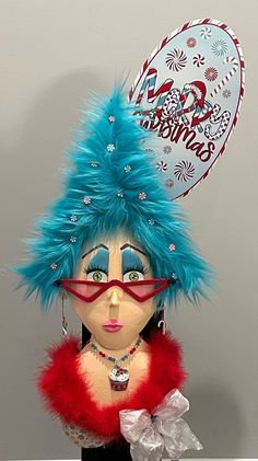 a doll with blue hair and red glasses on top of a white table next to a balloon