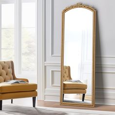 a large gold framed mirror sitting on top of a floor next to a chair and ottoman