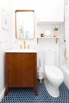 a white toilet sitting next to a sink in a bathroom under a mirror and a wooden cabinet