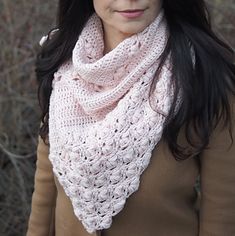 a woman wearing a pink crocheted cowl and holding a brown handbag