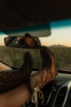 a woman taking a selfie in the rear view mirror of her car while driving