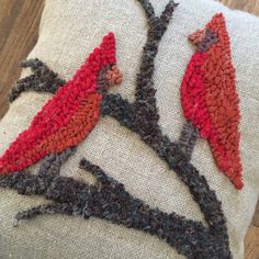 two red birds sitting on top of a tree branch embroidered onto a white pillow cover