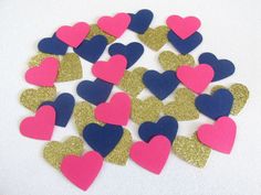 pink, blue and gold heart confetti on a white table with glitter hearts