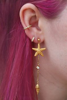 Channel your inner mermaid by rocking my under the sea drops! Featuring handmade starfish, spiral shells and pearls inspired by the ocean floor. The starfish are handmade by an indigenous Thai hill tribe from sterling silver, then plated in 14k gold in Rhode Island. They are very lightweight but perfect for a night out dancing as they have immediate movement on their own! These lovely long earrings pop out when you walk and show up even with long hair worn down when other earrings tend to disappear in photos. Manmade pearls Sterling silver starfish & shells handmade and 14k gold plated 14k gold-fill nickel-free posts with strong rubber backs which are more secure than metal backs 3.25" long Ocean-inspired Starfish Dangle Jewelry, Bohemian Gold Starfish Jewelry, Ocean-inspired Dangle Pearl Drop Jewelry, Ocean-inspired Pearl Drop Dangle Jewelry, Gold Starfish Charm Drop Earrings, Gold Starfish Jewelry With Pearl Charm, Shells And Pearls, Spiral Shell, Ocean Floor