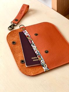 an orange purse with a passport and keychain attached to it on a table