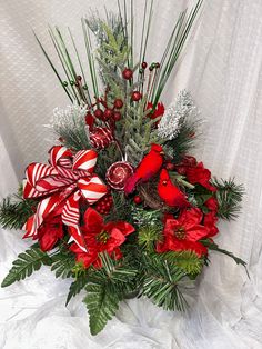 a christmas arrangement with candy canes, greenery and red flowers on a white background