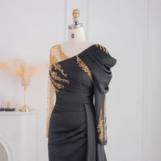 Luxury Black Satin Design: The dress features a luxurious black satin material, exuding elegance and sophistication, making it an ideal choice for upscale events and special occasions, particularly for weddings. Mermaid Silhouette: The mermaid silhouette elegantly accentuates your figure, creating a striking and alluring look that ensures you stand out and feel radiant at any event. Beaded Overskirt Detail: The addition of a beaded overskirt adds an element of drama and elegance, creating a stun Black Evening Mother Of The Bride Dress For Wedding, Black Mother Of The Bride Dress For Evening Wedding, Black Satin Evening Dress With Fitted Bodice, Satin Mother Of The Bride Dress For Evening Gala, Satin Mermaid Evening Dress For Prom Season, Satin Mermaid Dress For Prom Evening, Black Satin Evening Dress For Party Season, Black Satin Gown For Prom Season, Black Satin Evening Dress For Prom