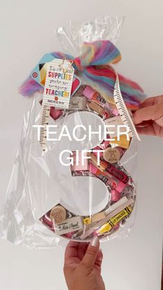 a person holding up a plastic bag filled with school supplies and the words teacher gift written on it