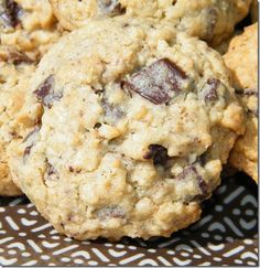 chocolate chip cookies are piled on top of each other in a plate with a brown and white pattern