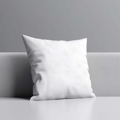 a white pillow sitting on top of a couch next to a gray wall and floor