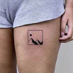 a person with a small tattoo on their thigh that has mountains and a sun in the background