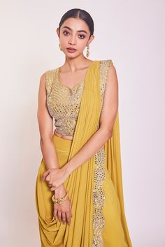 Yellow pre-draped saree with mirror and cutdana embroidery on the border. Comes with embroidered sleeveless blouse.
Component: 2
Pattern: Embroidery
Type Of Work: Mirror and Cutdana
Neckline: Leaf
Sleeve Type: Sleeveless
Fabric: Lycra
Color: Yellow
Other Details: 
Saree with scalloped border
Mirror and cutdana embroidered blouse
V neck back with dori
Occasion: Mehendi and Haldi - Aza Fashions Anarkali Draped Dupatta With Mirror Work, Bollywood Style Top With Traditional Drape And Dupatta, Anarkali Dupatta With Mirror Work, Bollywood Style Traditional Drape Top With Dupatta, Traditional Bollywood Tops With Dupatta, Festive Draped Sharara With Mirror Work, Bollywood Style Draped Sharara With Mirror Work, Draped Lehenga With Mirror Work In Georgette, Bollywood Style Draped Choli With Mirror Work