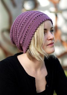 a woman with blonde hair wearing a purple knitted hat and looking off to the side