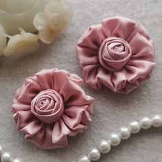 two pink flowers and pearls on a table