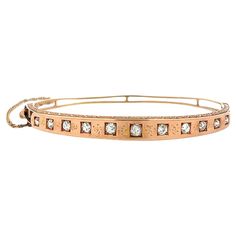 This elegant Victorian 14 karat rose gold hinged bangle features eleven old mine cut diamonds, totaling approximately 0.75 carats, with matching I/J color and VS-SI1 clarity. The bangle gracefully tapers from 5.9mm at the top to 2.8mm at the bottom and is adorned with a delicate scroll design on the sides, complemented by light stamping between the diamonds. The inside of the bangle measures 2.25 inches and 2 inches in height and would accommodate the wrist accordingly. It is secured with a hidden tongue clasp and a 4-inch safety chain and weighs 10.41 grams. Rose Gold Bangle Bracelet, White Gold Bangle, Platinum Bracelet, Rose Gold Bangle, Yellow Gold Bangle, Pearl Bangle, Diamond Bangles Bracelet, Safety Chain, Scroll Design