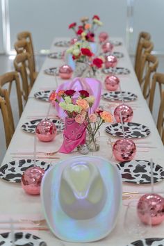 the table is decorated with pink, white and black plates and flowers in vases