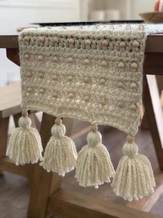 a crocheted table runner with tassels hanging from it